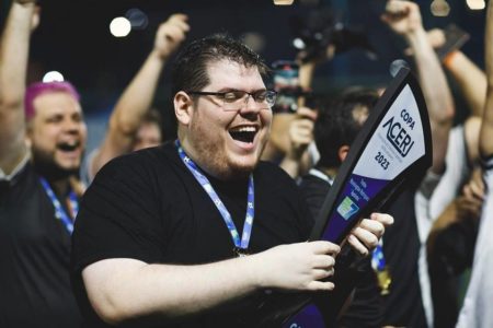 Foto colorida de Casimiro Miguel segurando troféu e sorrindo, com crachá no pescoço - Metrópoles