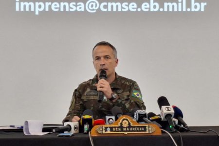 Imagem colorida mostra o General de Brigada Maurício Vieira Gama, Chefe do Estado-Maior do CMSE, um homem branco, vestido com uniforme do exército, com vários microfones à sua frente - Metrópoles