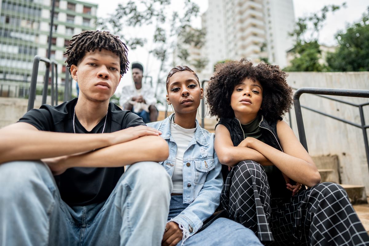 Imagem em cor, três adolescentes sentados na escada - Metrópoles