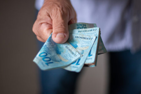 Homem mostra várias notas de 100 reais - Metrópoles