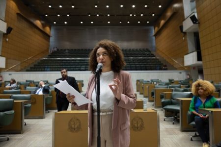 Fotografia colorida mostra a deputada Monica Seixas, do PSol, uma mulher negra de canelos cacheados na altura do ombro, vestindo blazer e calça rosa e uma camisa azul, e discursando no plenário da Alesp - Metrópoles