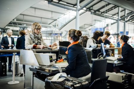 Mulher comprando passagem aérea em guichê no aeroporto - Metrópoles