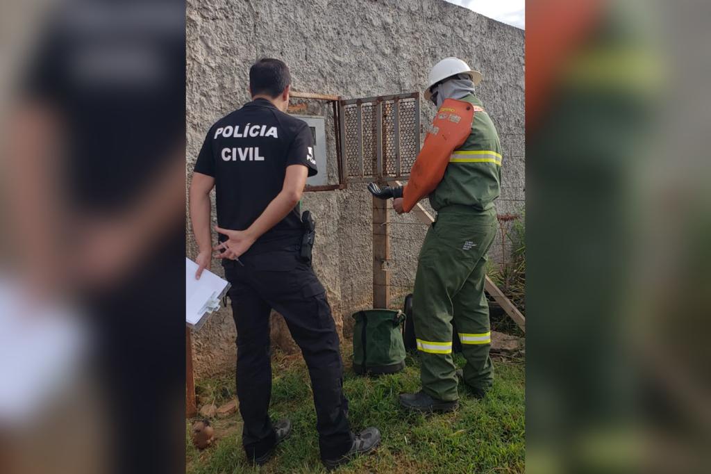 Imagem colorida de pessoas com uniforme da Neoenergia e da PCDF verificando relógio de energia - metrópoles