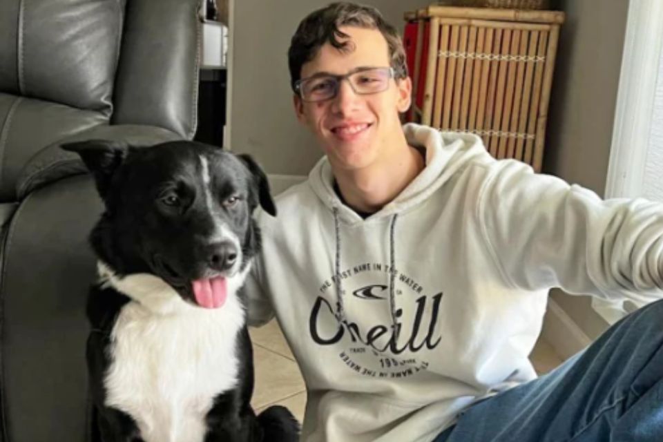 Foto colorida de um jovem com cachorro - Metrópoles