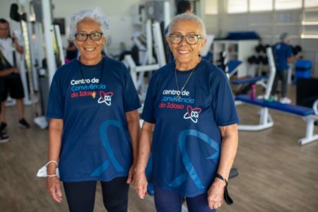 Imagem colorida de idosas vestidas de azul, uma do lado da outra em sala de musculação - Metrópoles