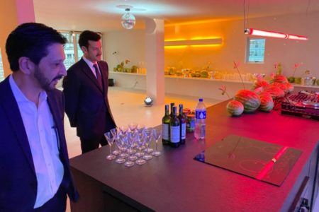 Imagem colorida mostra Ricardo Nunes, homem branco, de cabelo e barba pretos, terno azul e camisa branca, em uma sala de festas minimalista com luzes neons, de frente para uma mesa com copos e garrafas de bebidas - Metrópoles