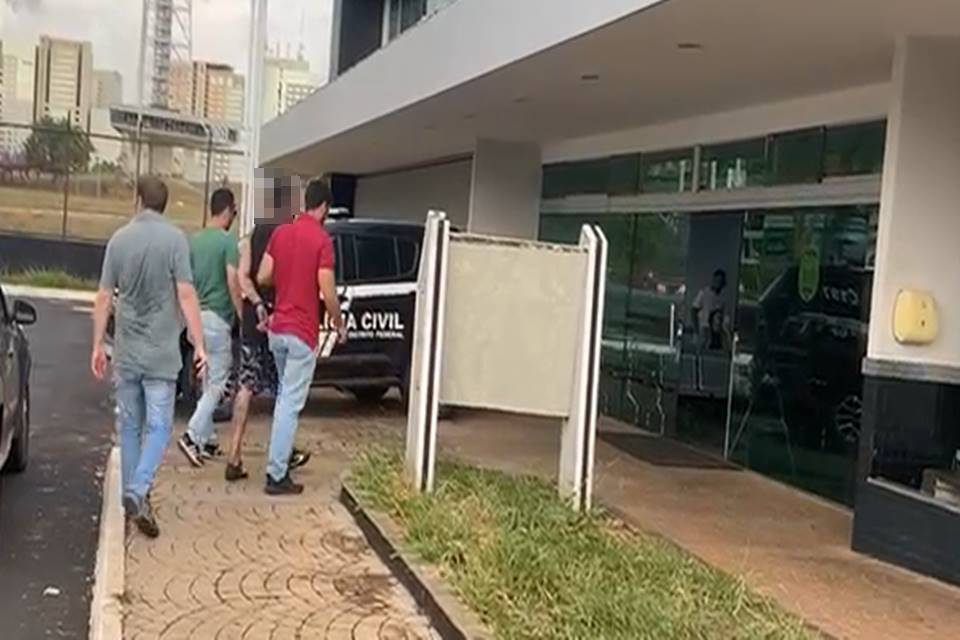 Homem é levado para porta da delegacia acompanhado de dois policiais