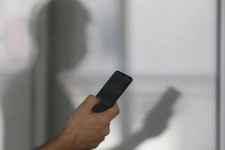 imagem colorida mostra silhueta de homem segurando o celular Minas Gerais