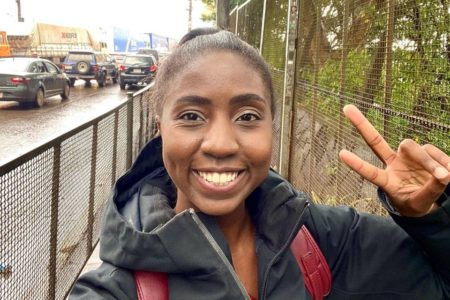 Foto colorida de Nataly Castro sorrindo e fazendo sinal de paz com a mão - Metrópoles