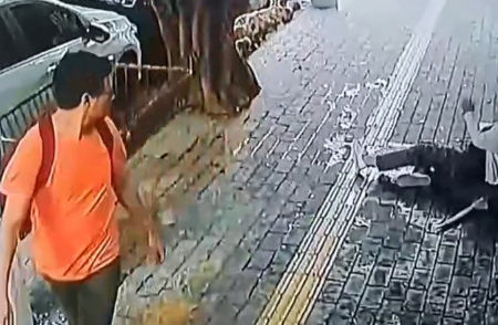 Homem de camiseta laranja olha para idosa caída no chão - Metrópoles