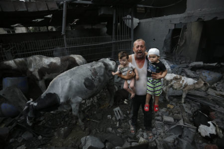 Imagem colorida mostra um homem segurando duas crianças feridas após bombardeio israelense na Faixa de Gaza - Metrópoles