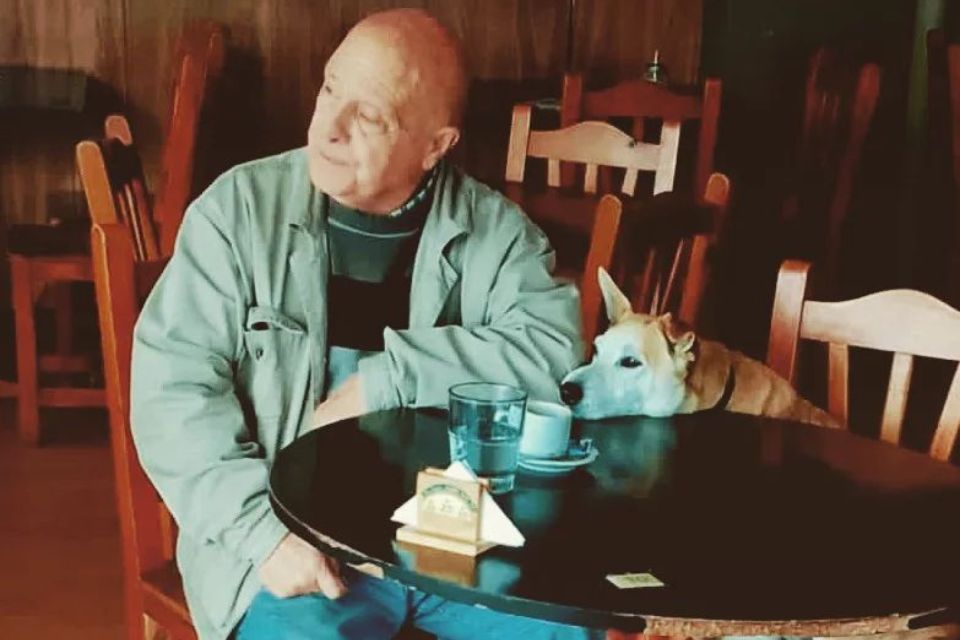 homem com cachorro sentado na mesa em restaurante argentino