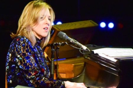 Foto colorida de Diana Krall tocando piano e cantando - Metrópoles