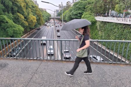 Imagem mostra mulher caminhando com guarda-chuva - Metrópoles