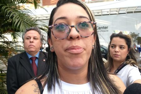 Imagem mostra mulher de óculos à frente de outras duas pessoas - Metrópoles