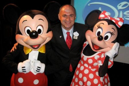 O escritor e pesquisador Claudemir Oliveira em foto colorida em meio dos personagens da Disney Mickey e Minnie