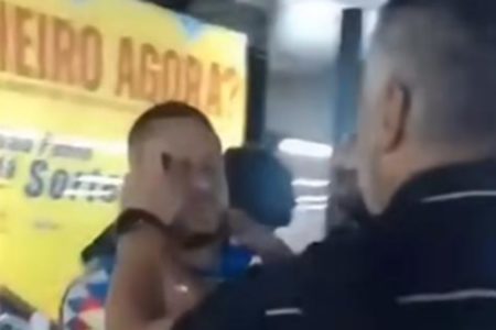 Imagem colorida mostra homem recebendo um spray químico na cara, jogado por um homem com uniforme de segurança do Metrô. A imagem é um frame de vídeo, em uma estação da rede - Metrópoles