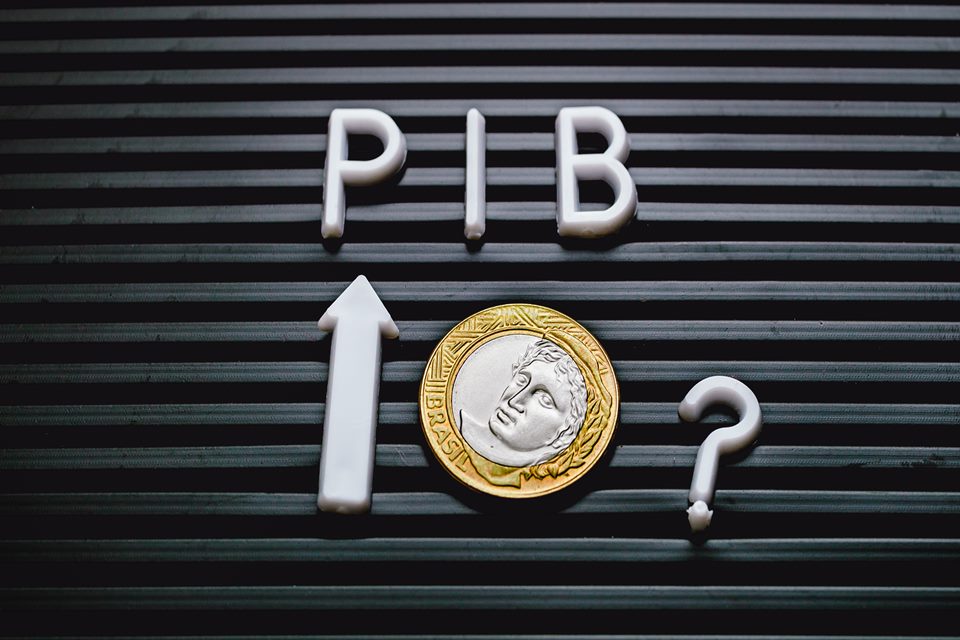 Imagem de uma moeda de 1 real. Acima dela, a palavra "PIB". Ao lado, uma seta apontando para cima. E, do outro lado, um ponto de interrogação - Metrópoles
