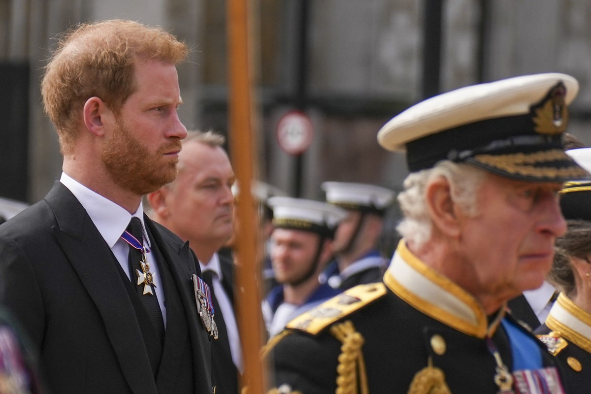 Foto colorida de homem ruivo, com terno e medalhas militares andando atrás de homem idoso com roupa militar - Metrópoles