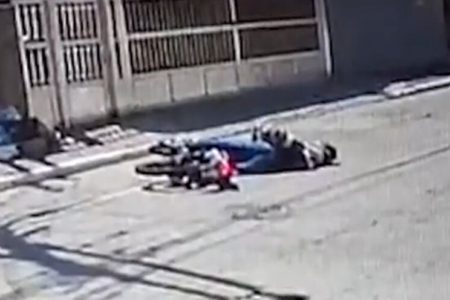 Em foto colorida jovem caído na rua ao lado de moto - Metrópoles