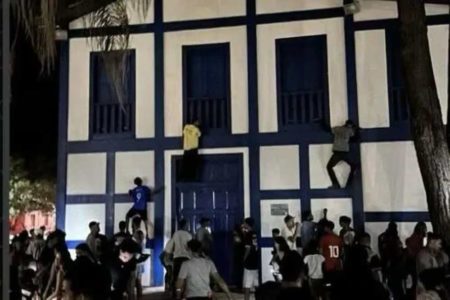 Na foto, pessoas escalam uma igreja