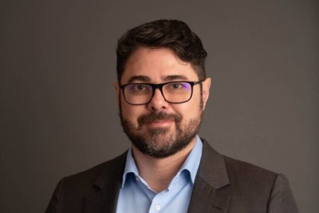 Foto colorida de homem branco com barba e óculos de terno e blusa azul - Metrópoles