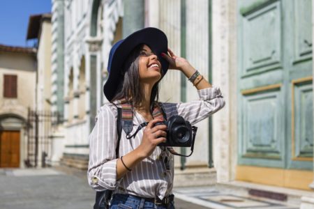Mulher morena está admirando um ponto turístico com uma câmera fotográfica nas mãos - Metrópoles