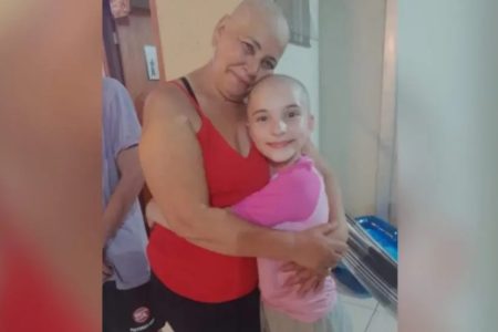 Foto de mulher e menina abraçadas, ambas estão com o cabelo raspado - Metrópoles