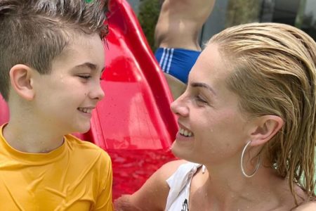 foto colorida do rosto de um menino sorrindo olhando para ana hickmann, os dois estão molhados em uma piscina - metrópoles