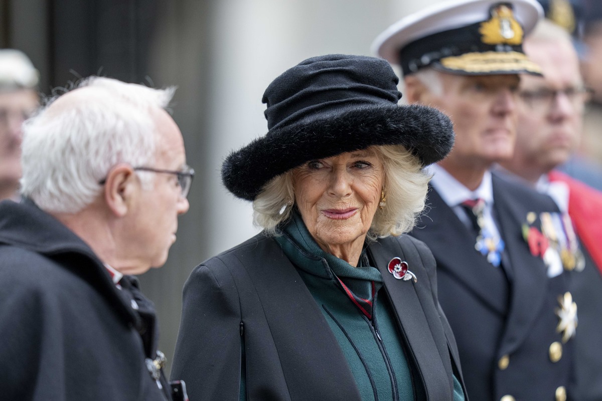 Rainha Camilla, uma mulher de cabelos brancos, idosa, está usando uma roupa e chapéu preto - Metrópoles