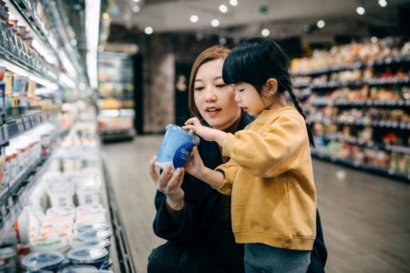 mulher e criança escolhendo iogurte no mercado