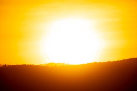 Foto colorida de um sol saindo por trás de um monte el niño - Metrópoles