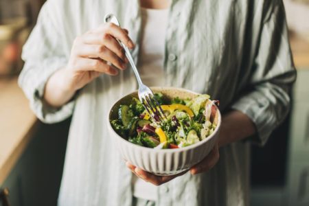 Foto colorida das mãos de uma mulher segurando um bowl com salada - Metrópoles