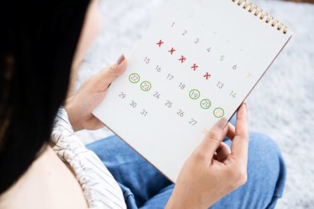 Foto de mulher de costas olhando calendário de ciclo menstrual - Metrópoles