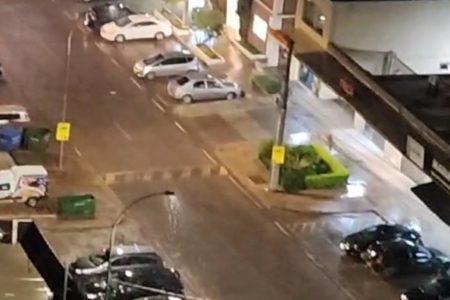 Foto colorida de rua com imagens de poste com gotas da chuva