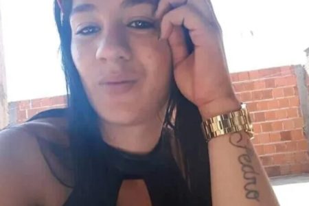 Selfie colorida mostra mulher de cabelo preto com a cabeça apoiada na mão. Ela tem um relógio dourado e uma tatuagem escrito "Pedro"