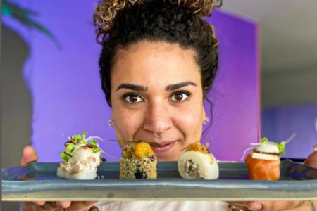 Foto colorida de uma mulher segurando sushi - Metrópoles