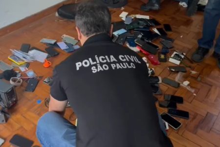 Foto colorida mostra policial se debruçando sobre celulares roubados espalhados pelo chão; número de furtos sobe em São Paulo - Metrópoles