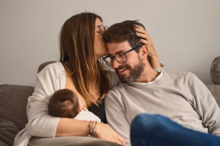 mulher amamenta bebê e beija cabeça de homem