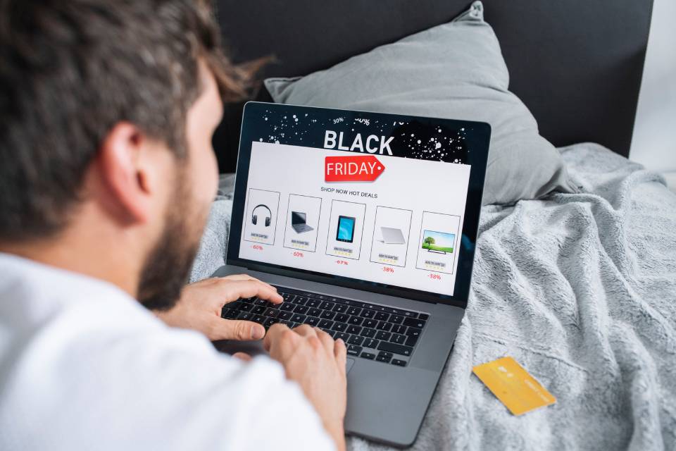 imagem colorida pessoa com notebook vendo ofertas da Black Friday - Metrópoles