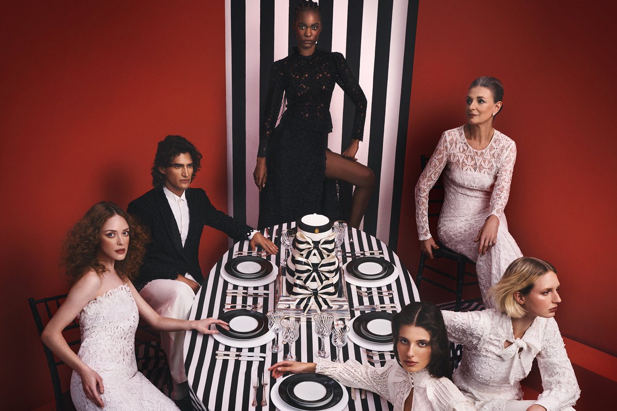 Em campanha de moda, modelos estão ao redor de mesa com utensílios e looks em preto e branco - Metrópoles