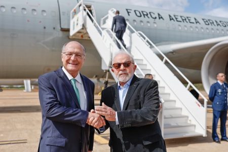 imagem colorida lula e alckmin de mãos dadas em frente a avião - metrópoles