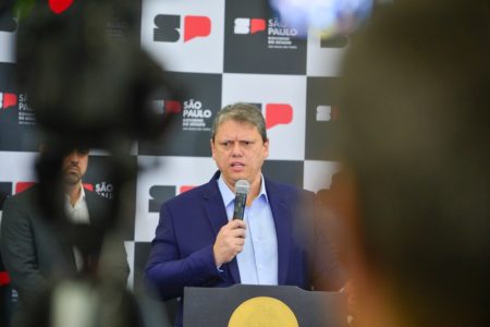 Imagem colorida mostra Tarcísio de Freitas, homem branco, grisalho, de terno azul marinho e camisa azul clara, entre câmeras de TV, dando uma entrevista - Metrópoles