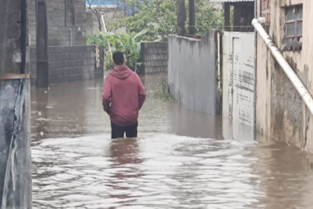 Imagem colorida de homem andando em rua alagada - Metrópoles