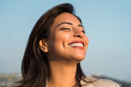 Mulher sorrindo para o nada com olhos fechados