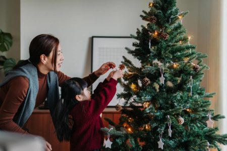 Foto de mulher e menina colocam enfeite em árvore de Natal - Metrópoles