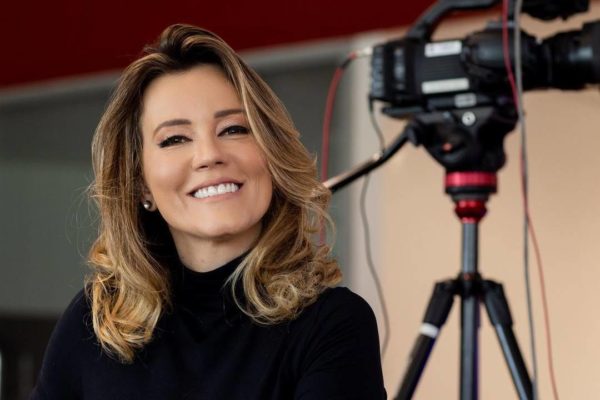 Foto colorida de Natuza Nery ao lado de câmera, sorrindo - Metrópoles