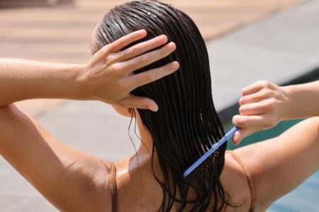 Mulher penteando o cabelo molhado no banho