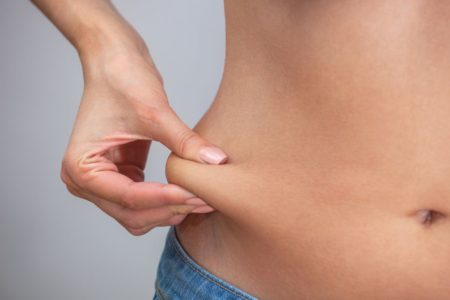 pessoa apertando gordura abdominal