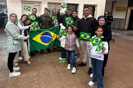 Grupo de pessoas sorrindo e segurando a bandeira do Brasil